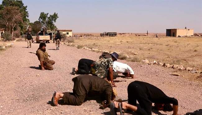 This undated image posted Wednesday, Aug. 27, 2014 by the Raqqa Media Center of the Islamic State group, a Syrian opposition group, which has been verified and is consistent with other AP reporting, shows fighters from the Islamic State group that captured the Tabqa air base from the Syrian government on Sunday, praying inside the air base, in Raqqa, Syria. A U.N. commission on Wednesday accused the extremist Islamic State organization of committing crimes against humanity with attacks on civilians, as pictures emerged of the extremists' bloody takeover of a Syrian military air base that added to the international organization’s claims.