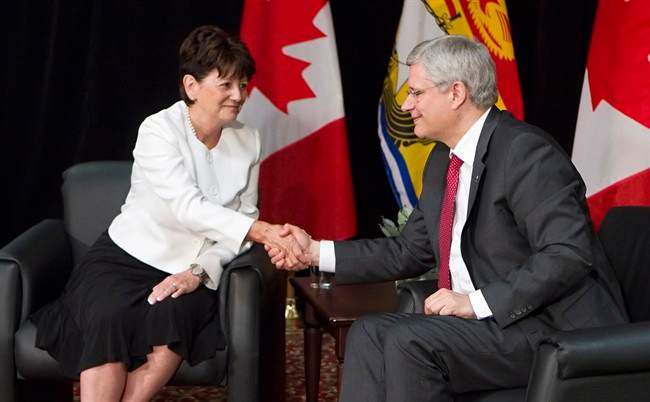 Prime Minister Stephen Harper, right, shakes hands with Jocelyne Roy-Vienneau, right, the new lieutenant governor of New Brunswick, at a news conference in Edmundston, N.B., on Friday, Aug. 8, 2014 . THE CANADIAN PRESS/Clement Allard.