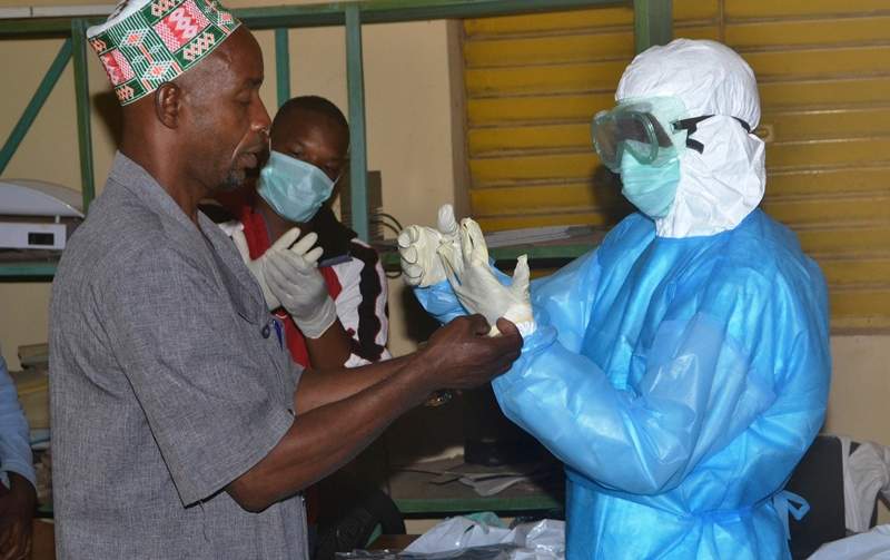 Health workers take off their protective suits as they finish their shifts at the Pita hospital on August 25, 2014. The worst-ever Ebola epidemic could cut economic output in four west African countries by between 1 percent and 1.5 percent of gross economic product, the African Development Bank said Tuesday. AFP PHOTO / CELLOU BINAN.