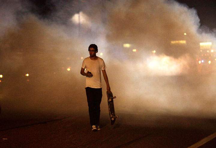 A man with a skateboard protesting Michael Brown’s murder walks away from tear gas released by police August 17, 2014 in Ferguson, Missouri.