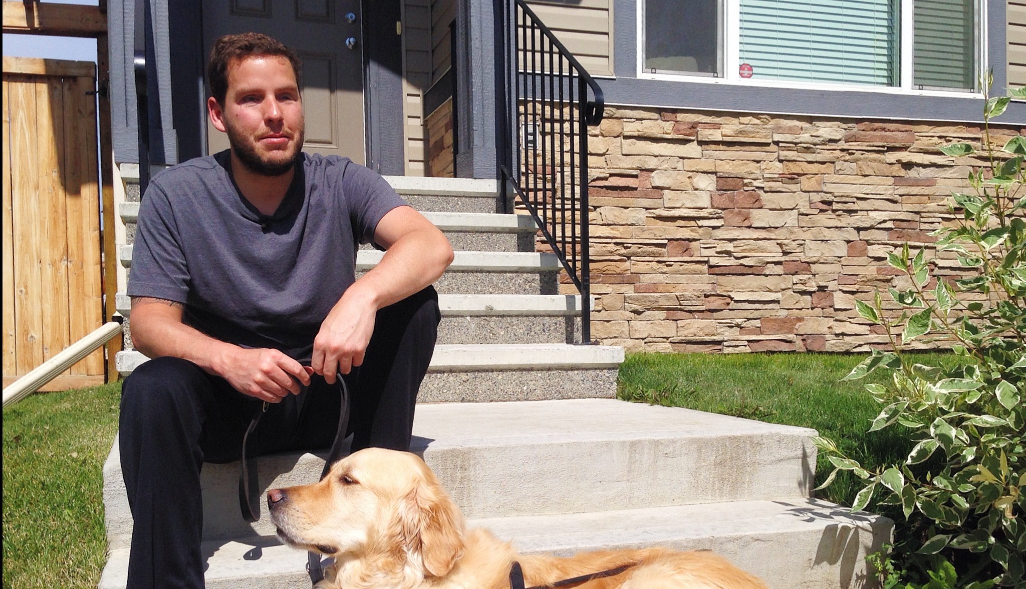 Jose Neto, sits with his guide dog on the front steps of his home. 