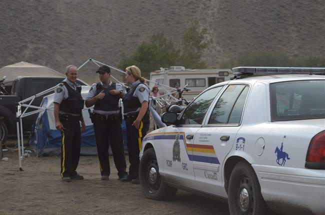 File photo: RCMP stand at the entrance to the camping area of the Boonstock Music and Art Festival in Penticton, B.C., where a 24-year-old woman from Leduc, Alberta died as the result of a drug overdose, early Saturday morning, Aug. 2, 2014. THE CANADIAN PRESS/Penticton Herald-James Miller.