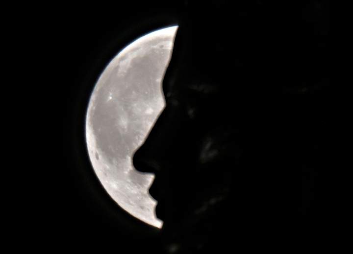 The supermoon rises through the clouds behind the "Motherland" statue, part of the WWII memorial complex, in Kiev, Ukraine, Sunday, Aug. 10, 2014.