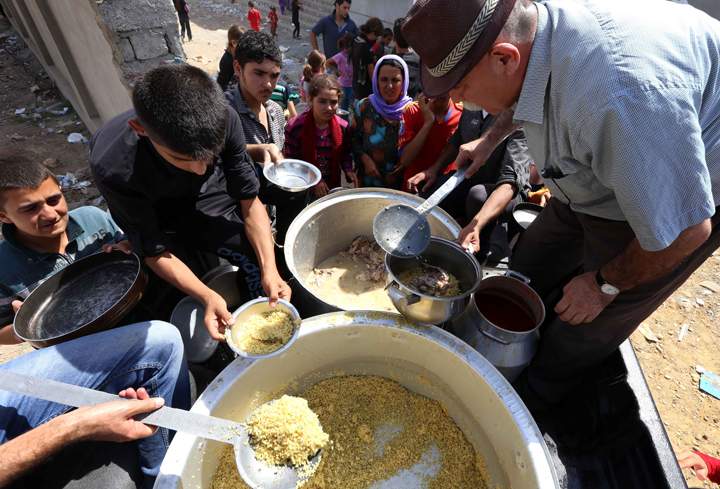 Iraqi Yazidi families who fled the violence in the northern Iraqi town of Sinjar, are given food at a school where they are taking shelter in the Kurdish city of Dohuk in Iraq's autonomous Kurdistan region, on August 5, 2014.