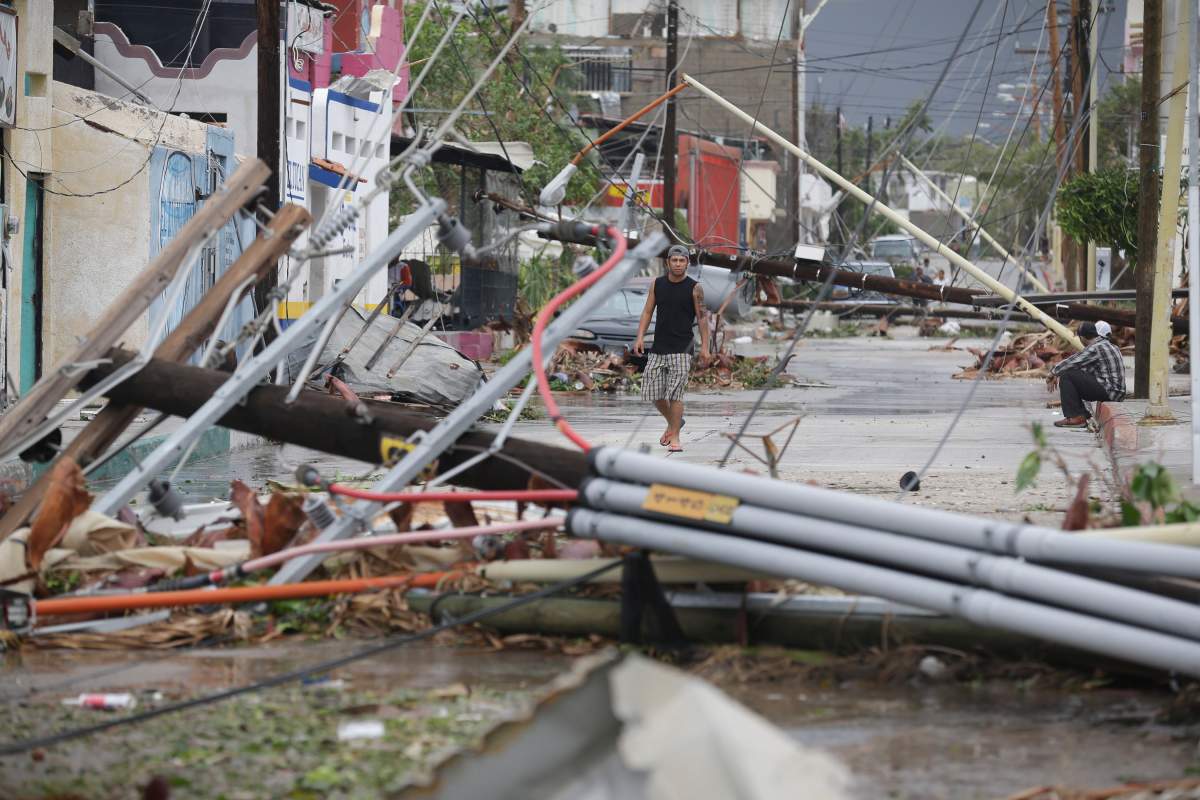 A man walks on a street where most power lines and light posts have been knocked down by Hurricane Odile, in Los Cabos, Mexico, Monday, Sept. 15, 2014. (AP Photo/Victor R. Caivano).