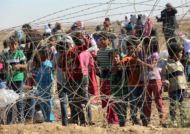 Several hundred Syrian refugees wait to cross into Turkey at the border in Suruc, Turkey, in September 2014.