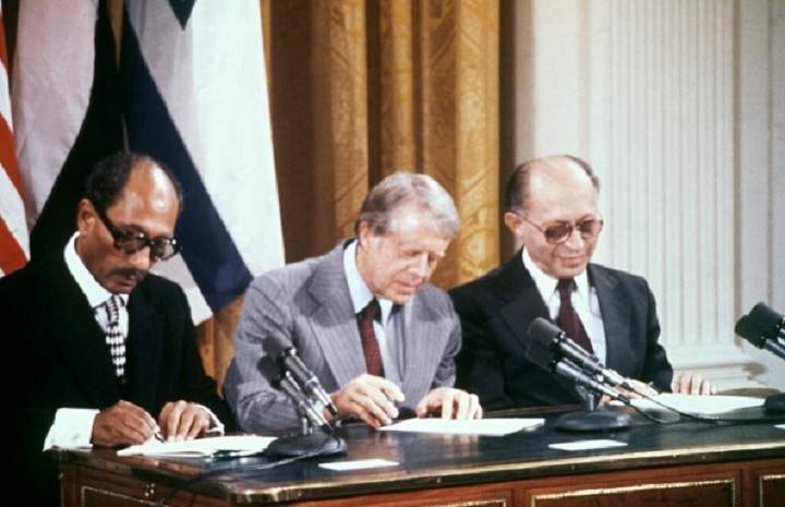 Egyptian President Anwar al-Sadat (L), Israeli Premier Menachem Begin (R) and US President Jimmy Carter (C) sign a peace agreement in the East Room of the White House, 18 September 1978.