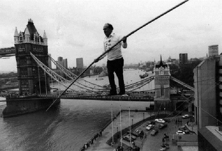 Karl Wallenda walking a tightrope from two corners of the Tower Hotel with Tower Bridge in the background in London, England.