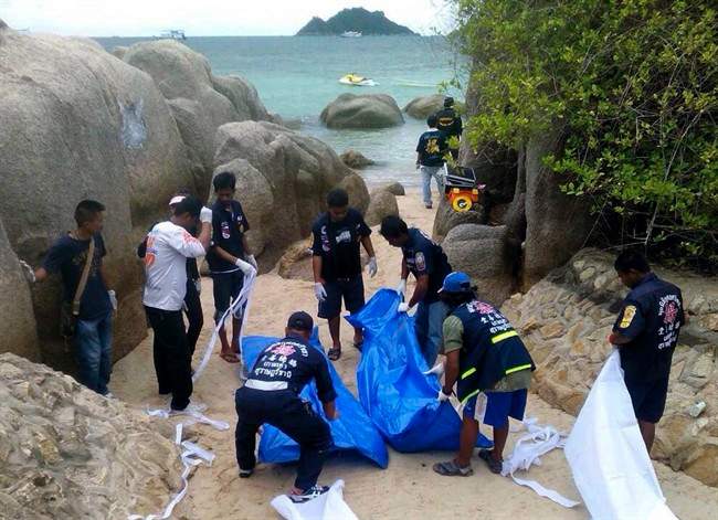 Thai officers work near the bodies of two British tourists Monday, Sept. 15, 2014 on a beach in Surat Thani province, southern Thailand. 