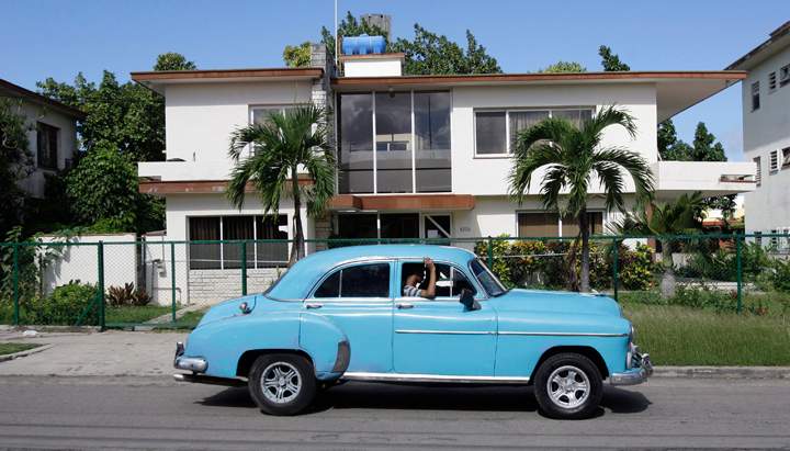 In this Friday Nov. 18, 2011 photo, a classic car drives in front of the headquarters of the firm Coral Capital Group in Havana. The government has given no information on probes of the investment firm Coral Capital Group, led by a Briton, Tri-Star Caribbean and Tokmakjian Group, two car dealerships run by Canadians.