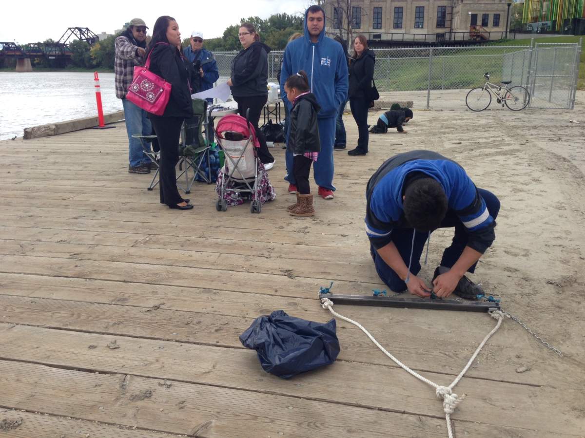 Kyle Kematch attaches hooks to chains in preparation for dragging the river.