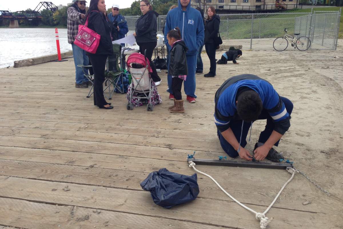 A volunteer attaches hooks to chains in preparation of dragging the river.