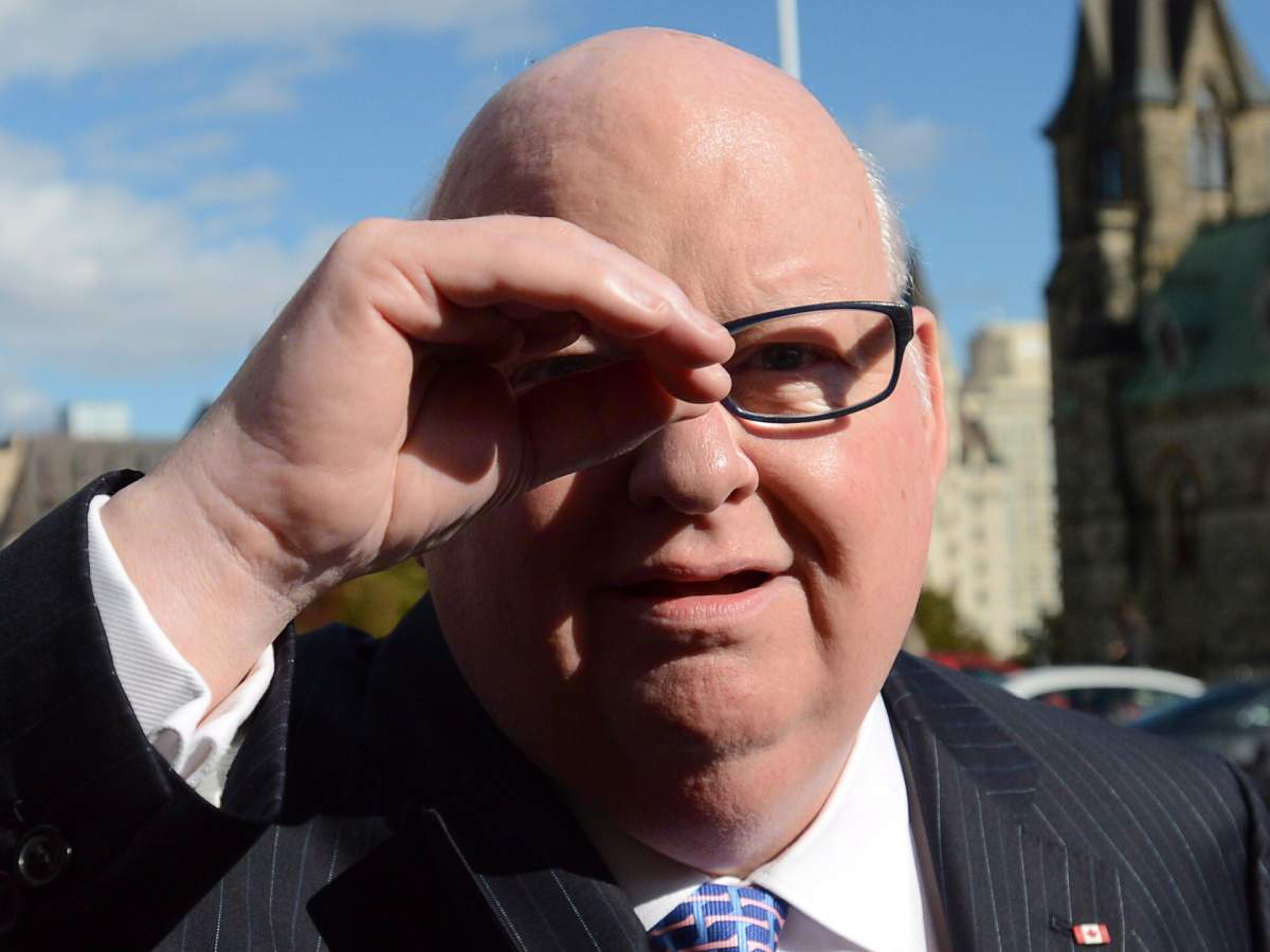 Sen. Mike Duffy shields his eyes as he arrives at the Senate on Parliament Hill in Ottawa on Tuesday, Oct. 22, 2013. THE CANADIAN PRESS/Sean Kilpatrick.