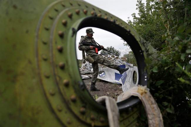 A Pro-Russian rebel looks at pieces of the Malaysia Airlines Flight 17 plane near village of Rozsypne, eastern Ukraine, on Sept. 9, 2014. 
