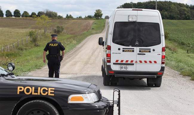 File photo of an Ontario Provincial Police officer standing beside an OPP van.