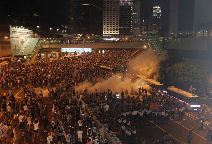 Riot police use tear gas against protesters after thousands of people blocked a main road at the financial central district in Hong Kong, Sunday, Sept. 28, 2014.