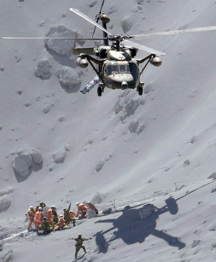 Rescuers help an injured person on Mount Ontake in central Japan, Sunday, Sept. 28, 2014.