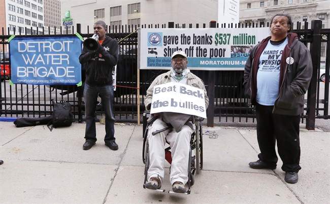 Demeeko Williams, left, of the Detroit Water Brigade talks into a megaphone during a rally outside federal courthouse in Detroit, Monday, Sept. 22, 2014. 