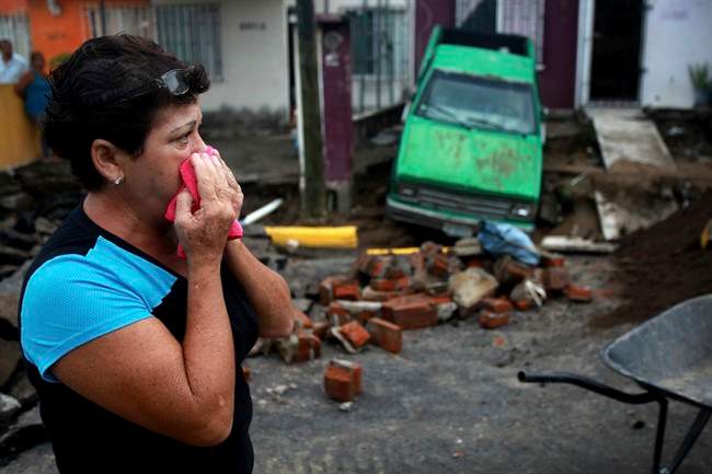 Maria del Carmen Gonzalez watches after part of a street and her home collapsed due to heavy rains in the Gulf port city of Veracruz, Mexico, Tuesday Sept. 2, 2014. 