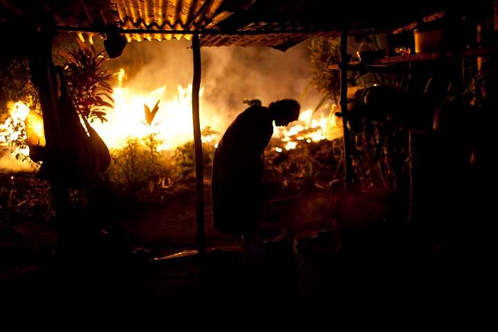 In this Sept. 26, 2013 photo, an Ashaninka Indian woman is silhouetted against a wall of flames caused by burning branches during a land clearing in Otari Nativo, Pichari district, Peru.
