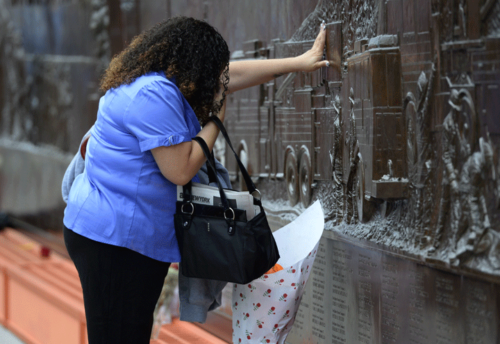 A woman lays flowers at the Fire Department of New York (FDNY) Memorial Wall Located at FDNY Engine 10 and Ladder September 11, 2014 on the 13th anniversary of the September 11, 2001 attacks.