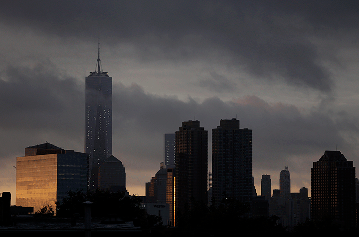 Storm clouds roll over 1 World Trade Center, left, seen from The Heights neighborhood of Jersey City, N.J., at sunrise, Thursday, Sept. 11, 2014.