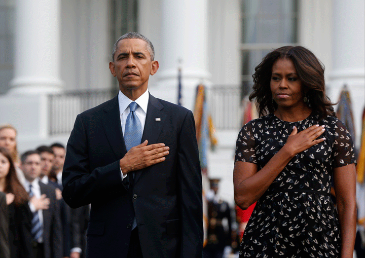 President Barack Obama and first lady Michelle Obama stand during the playing of Taps on the South Lawn of the White House in Washington, Thursday, Sept. 11, 2014, as they observe a moment of silence to mark the 13th anniversary of the 9/11 attacks. (Photo credit: AP Photo/Charles Dharapak)
