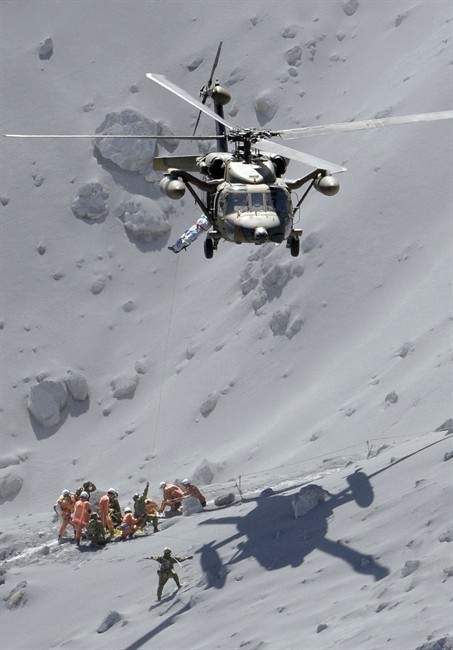 Rescuers help an injured person on Mount Ontake in central Japan, Sunday, Sept. 28, 2014. Mount Ontake erupted shortly before noon Saturday, spewing large white plumes of gas and ash high into the sky and blanketing the surrounding area in ash.
