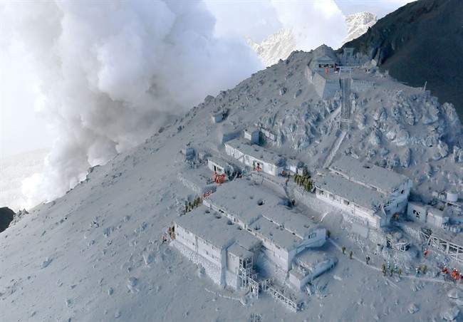 Firefighters and members of Japan’s Self-Defense Forces conduct a rescue operation at a cabin near the peak of Mount Ontake as plumes of smoke billow in central Japan, Sunday, Sept. 28, 2014.