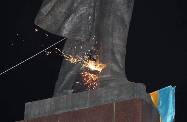 An activist dismantles Ukraine's biggest monument to Lenin at a pro-Ukrainian rally in the central square of the eastern city of Kharkiv, Ukraine, Sunday, Sept.28, 2014.