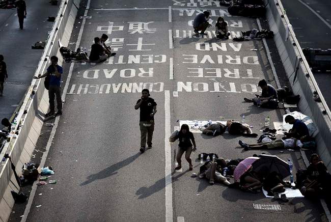 Student activists sleep, sit and walk on a road near the government headquarters where pro-democracy activists have gathered and made camp, Tuesday, Sept. 30, 2014, in Hong Kong.