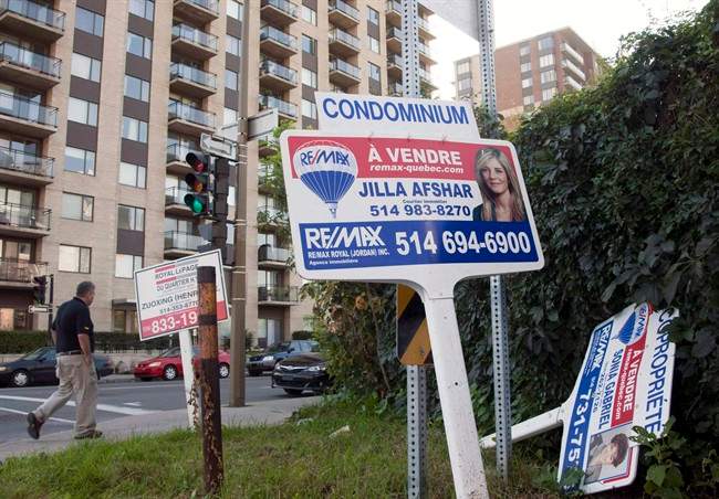A sale signs stand in front of a condominium.