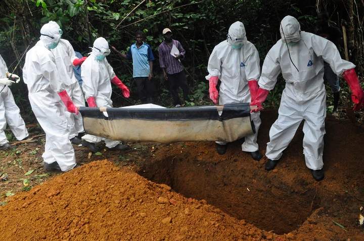 A burial team in protective gear bury the body of woman suspected to have died from Ebola virus in Monrovia, Liberia. Saturday, Oct, 18, 2014. 