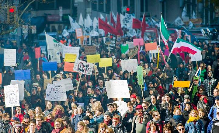 Protesters hold up signs during an anti-austerity demonstration in Montreal Friday, October 31, 2014.