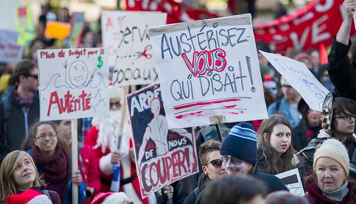 Protesters hold up signs during an anti-austerity demonstration in Montreal Friday, October 31, 2014.