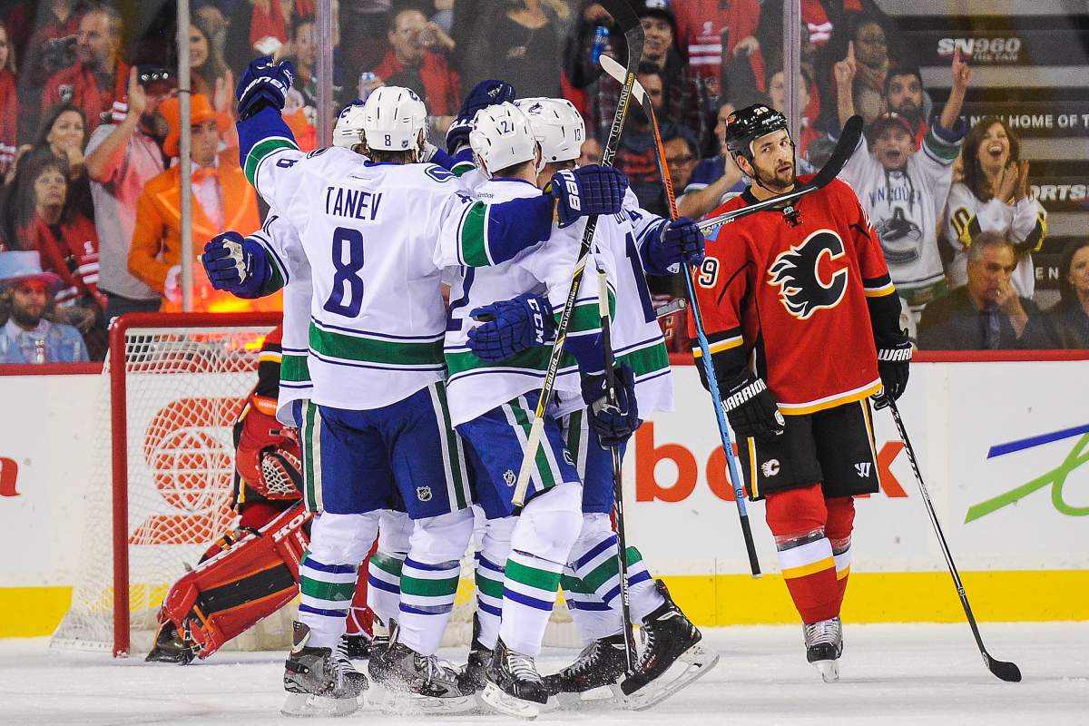 CALGARY, AB - OCTOBER 8: The Vancouver Canucks celebrate the goal of Alex Burrows #14 as a dejected Deryk Engelland #29 of the Calgary Flames skates away during an NHL game at Scotiabank Saddledome on October 8, 2014 in Calgary, Alberta, Canada. (Photo by Derek Leung/Getty Images).