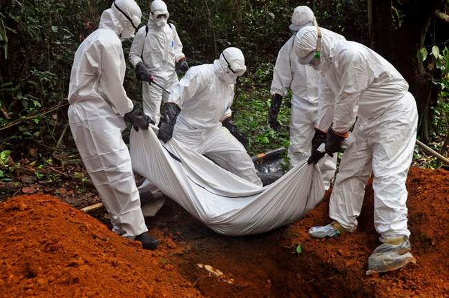 Health workers bury the body of a woman who is suspected of having died of the Ebola virus in Bomi county, on the outskirts of Monrovia, Liberia, Monday, Oct. 20, 2014.