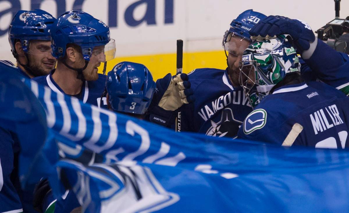 Vancouver Canucks left wing Chris Higgins (20) celebrates his teams win with fellow Canucks following a shootout against the Edmonton Oilers in Vancouver, B.C. Saturday, Oct. 11, 2014. Higgins scored the game winning goal in the shootout. THE CANADIAN PRESS/Jonathan Hayward.
