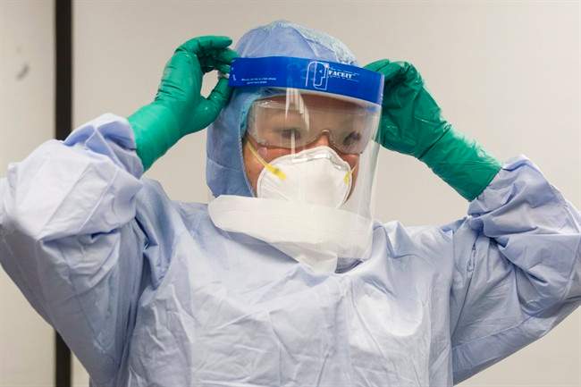 A healthcare professional adjusts her mask during a demonstration of Personal Protective Equipment (PPE) procedures at Toronto Western Hospital on Friday October 17, 2014. 