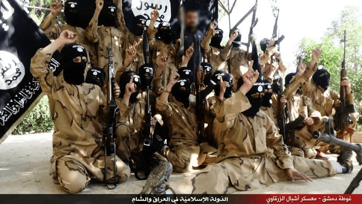 Children pose with guns in front of ISIS flags at a purported training camp in Syria. The image comes from a propaganda video released by ISIS.