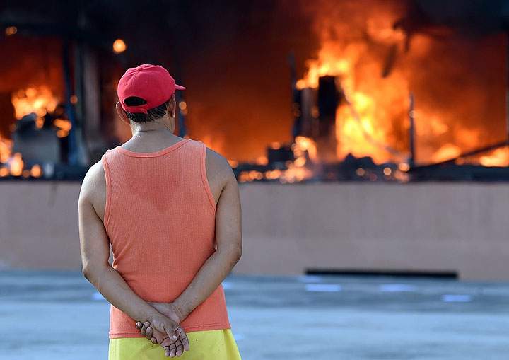 A man stares at the blazing Municipal Palace in Chilpancingo on October 13, 2014 after students set it on fire during a protest to demand the finding of the 43 peers missing since an attack by rogue officers earlier this month. Authorities are investigating whether the students were buried in mass graves found outside Iguala, a city 200 kilometers (125 miles) south of Mexico City.