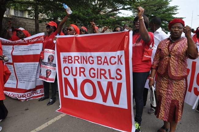 In this file photo taken Tuesday, Oct. 14, 2014, people demonstrate calling on the Nigerian government to rescue girls taken from a secondary school in Chibok region, in the city of Abuja, Nigeria. Islamic extremists killed 35 people and kidnapped at least 185, fleeing residents said Thursday of an attack near the town where nearly 300 schoolgirls were taken hostage in April.