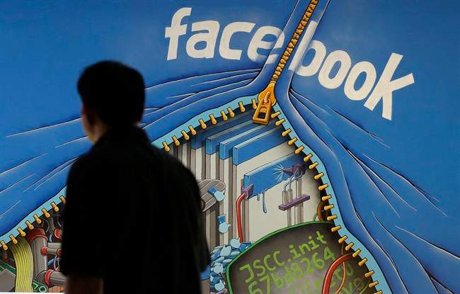 In this June 11, 2014 photo, a man walks past a mural in an office on the Facebook campus in Menlo Park, Calif. Facebook reports quarterly earnings on Tuesday, Oct. 28, 2014.
