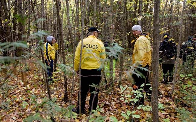 Police officers from Toronto Police and the OPP search a wooded area in Springwater Township, Ont., on Wednesday, Oct. 8, 2014. 