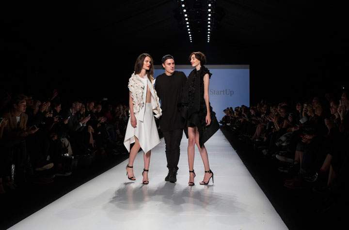 Designer Sid Neigum stands with two models after winning the Mercedes-Benz StartUp show during Toronto Fashion Week in Toronto on Monday, October 20, 2014.