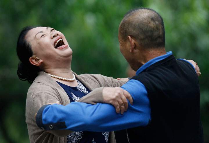 A woman laughs during a social dance with a man at Ritan Park in Beijing, China Thursday, Oct. 30, 2014.