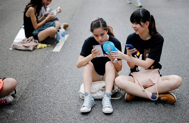 Student pro-democracy activists use their smartphones while sitting on the streets near the government headquarters, Thursday, Oct. 2, 2014 in Hong Kong. The Chinese government might be using smartphone apps to spy on pro-democracy protesters in Hong Kong, a U.S. security firm says. The applications are disguised as tools created by activists to protests, said the firm, Lacoon Mobile Security. The firm said that once downloaded, they give an outsider access to the phone's address book, call logs and other information.