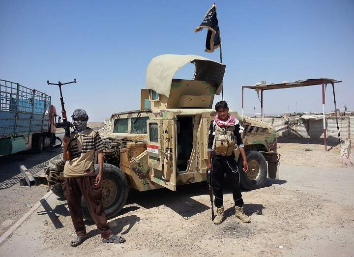 Islamic State militants stand with a captured Iraqi Army Humvee at a checkpoint outside Beiji refinery, some 250 kilometers north of Baghdad, Iraq.