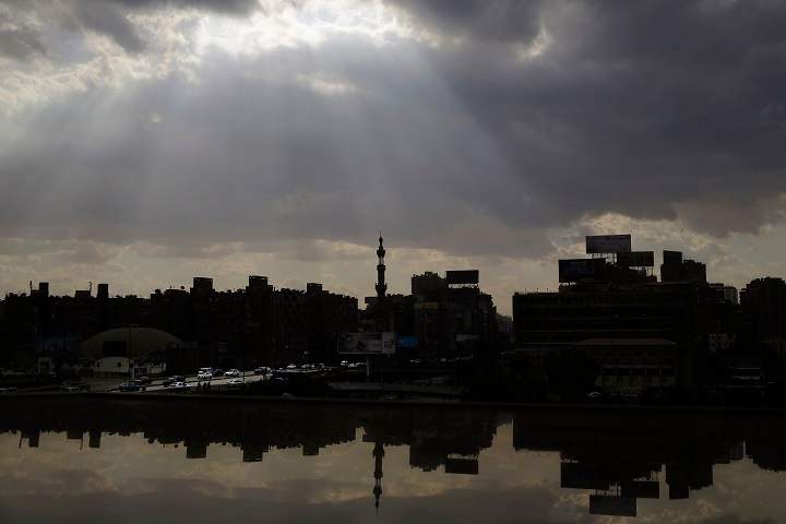 The sun's rays peep through the clouds over buildings in Giza, Cairo's neighboring city, seen through a window of a building in Cairo, Egypt, Friday, Oct. 31, 2014.