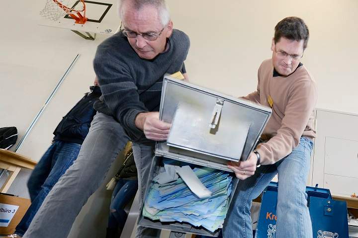 A ballot box is emptied at a voting centre in Zurich, Switzerland, Sunday Nov. 30, 2014.